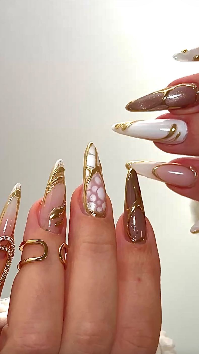 Lange Nägel in Nude mit goldenen Linien und Steinchen